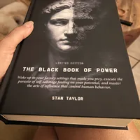Customer-uploaded image. Click to see more details. The image represents: A person holding a black book titled "The Black Book of Power Limited Edition" by Stan Taylor, featuring a classical statue face on the cover