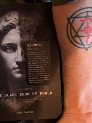 Customer-uploaded image. Click to see more details. The image represents: A book titled "The Black Book of Power" by Stan Taylor next to a person's arm showing a circular tattoo with geometric patterns in black and red ink.