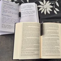 Customer-uploaded image. Click to see more details. The image represents: Open notebook with handwritten notes alongside an open book on a decorative surface with leaf patterns
